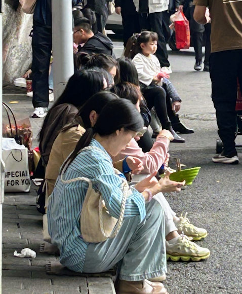 重慶・眼鏡小麺前の道路で食べる人たち